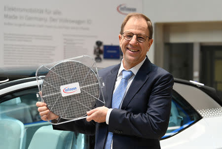 Reinhard Ploss, CEO of German semiconductor manufacturer Infineon, holds a wafer while posing for pictures at the company's annual shareholder meeting in Munich, Germany February 21, 2019. REUTERS/Andreas Gebert