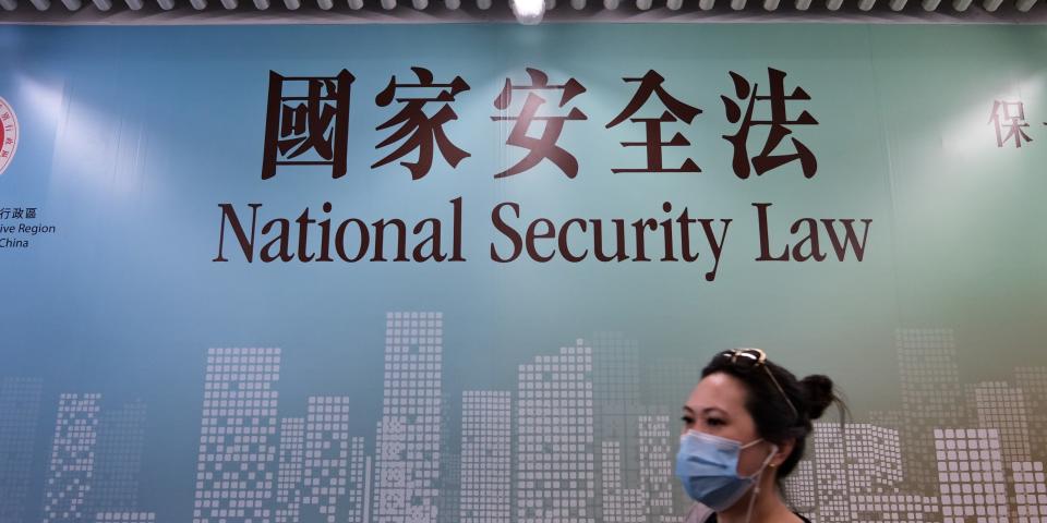 A woman walks past a poster for the National Security Law in Hong Kong on July 28, 2020. - The European Union will restrict exports to Hong Kong of equipment that could be used for surveillance and repression after Beijing imposed a controversial new security law, diplomatic sources said on July 28. (Photo by Anthony WALLACE / AFP) (Photo by ANTHONY WALLACE/AFP via Getty Images)