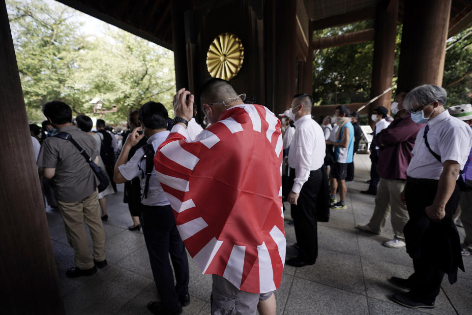 One of visitors carries a rising sun flag as he enters Yasukuni Shrine Saturday, Aug. 15, 2020, in Tokyo. Japan marked the 75th anniversary of the end of World War II. (AP Photo/Eugene Hoshiko)