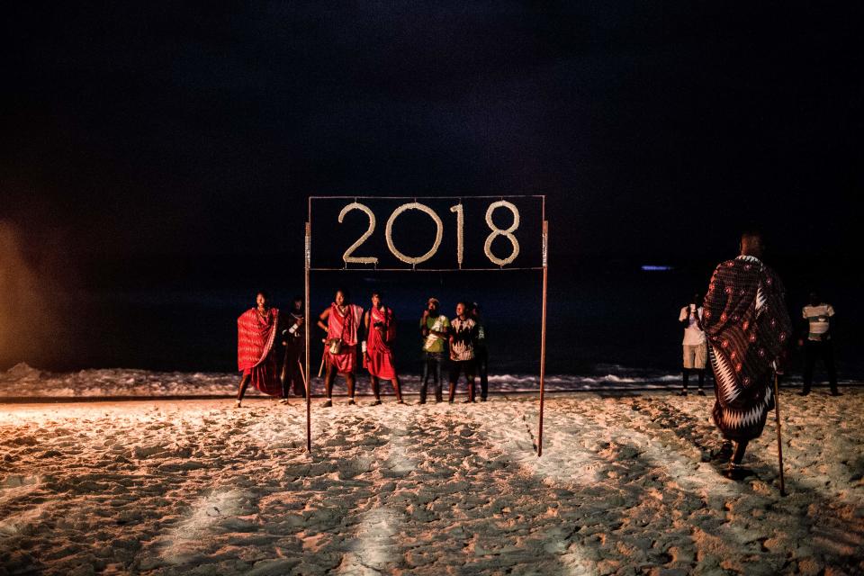 <p>People wait for a moment to light a sign that reads 2018 during the New Year’s Eve celebration on Nungwi Beach in Zanzibar, Tanzania, on December 31, 2017. (Photo: Gulshan Khan/AFP/Getty Images) </p>