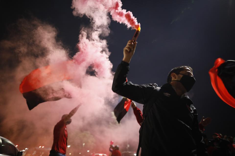 A man wearing a protective face mask holds a flare during a caravan organized by the soccer club fans of Newell's Old Boys in the hometown of Leonel Messi, in Rosario, Argentina, Thursday, Aug. 27, 2020. Fans hope to lure him home following his announcement that he wants to leave Barcelona F.C. after nearly two decades with the Spanish club. (AP Photo/Natacha Pisarenko)