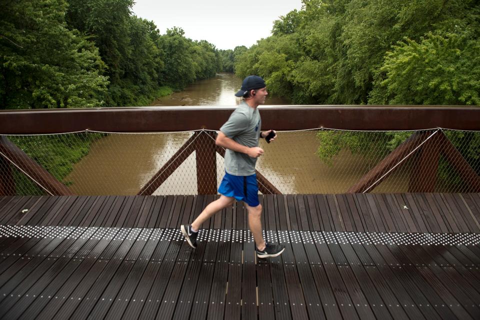 Devin Donaldson jogs across a bridge spanning the Wolf River on a section of the Wolf River Greenway near Humphreys Boulevard and Walnut Grove Road on July 3, 2015.