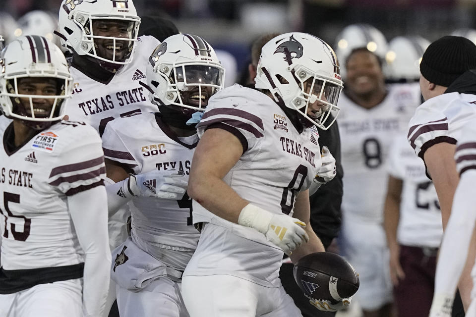 Texas State linebacker Brian Holloway (0) is congratulated by teammates after returning an interception for a touchdown against Rice during the first half of the First Responder Bowl NCAA college football game Tuesday, Dec. 26, 2023, in Dallas. (AP Photo/LM Otero)