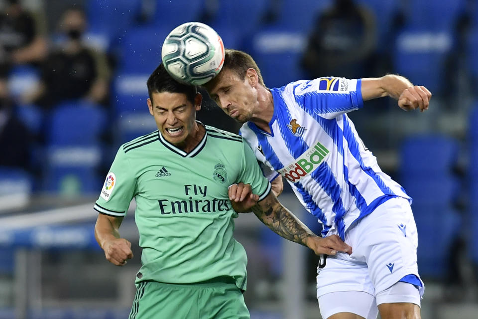 James Rodríguez (izquierda) del Real Madrid disputa un balón con Nacho Monreal de la Real Sociedad en el partido por la Liga de España en San Sebastián, el domingo 21 de junio de 2020. (AP Foto/Alvaro Barrientos)