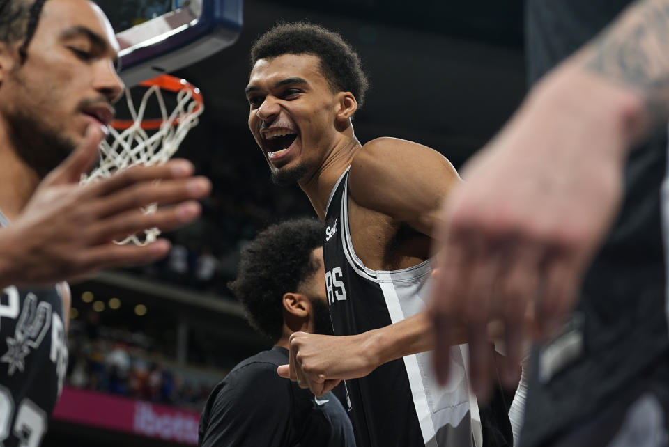 San Antonio Spurs center Victor Wembanyama, center, jokes with teammates before their NBA basketball game against the Denver Nuggets on Tuesday, April 2, 2024, in Denver. (AP Photo/David Zalubowski)