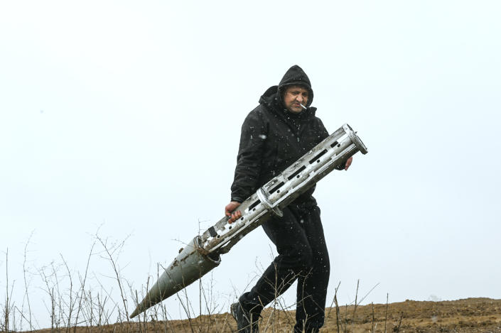 A Ukrainian civilian holds an empty Russian cluster munition rocket (Justin Yau/Sipa via AP File)