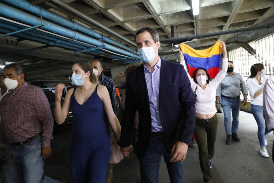 Opposition leader Juan Guaido and his wife Fabiana Rosales walk in the parking lot of their residential building after holding an impromptu press conference in Caracas, Venezuela, Monday, July 12, 2021. Guaido said security forces threatened his driver as he arrived home Monday. (AP Photo/Ariana Cubillos)