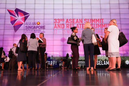 Delegates stand next to the ASEAN Summit signage at Suntec Convention Centre in Singapore, November 12, 2018. REUTERS/Athit Perawongmetha