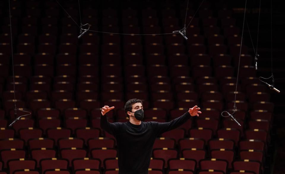 Indianapolis Symphony Orchestra conductor Jacob Joyce raises his arms while conducting a dress rehearsal March 10, 2021, at the Hilbert Circle Theatre in downtown Indianapolis.