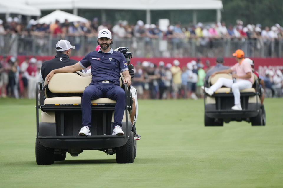 Adam Hadwin, left, and Rickie Fowler are driven to the 18th tee to compete with Collin Morikawa for the first playoff hole during the final round of the Rocket Mortgage Classic golf tournament at Detroit Country Club, Sunday, July 2, 2023, in Detroit. (AP Photo/Carlos Osorio)