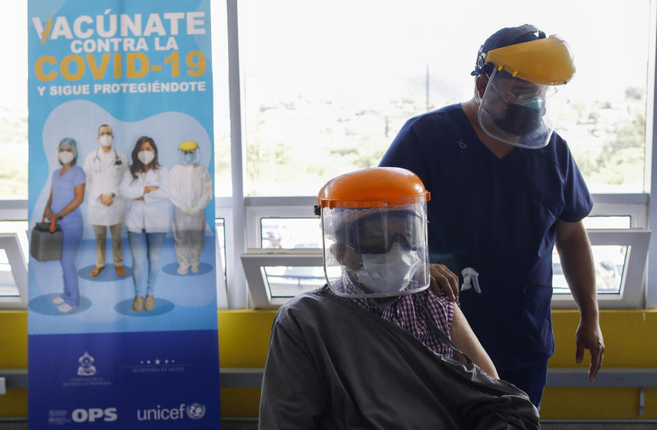 Roberto Maradiaga, 70, a retired doctor, is helped by his son Luis Roberto, while he waits for the Russian COVID-19 vaccine Sputnik V, as part of a vaccination campaign in Tegucigalpa, Honduras, Friday, April 23, 2021. Honduras has obtained a paltry 59,000 vaccine doses for its 10 million people. Similar gaps in vaccine access are found across Africa, where just 36 million doses have been acquired for the continent's 1.3 billion people, as well as in parts of Asia. (AP Photo/Elmer Martinez)