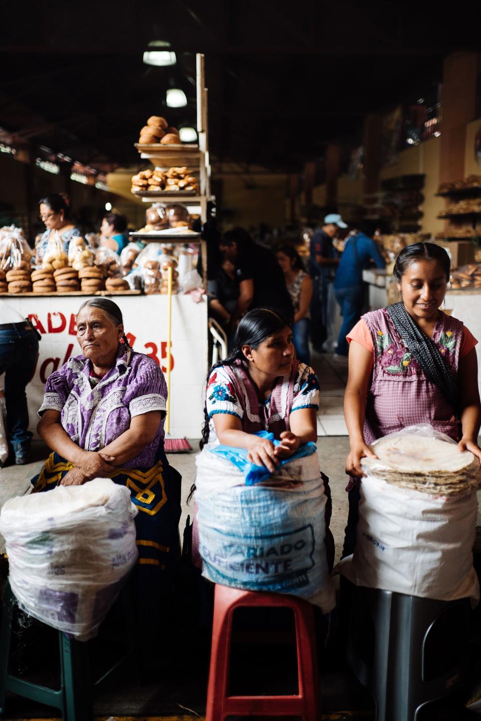 Inside the main food hall at the Sunday market in Tlacolula, women sell tortillas to those who have already visited the dozens of meat, bread, and vegetable stalls, and wish to use the many cooking stations located inside. The starkness of the age difference between the women and their beautiful attire is what caught my eye.