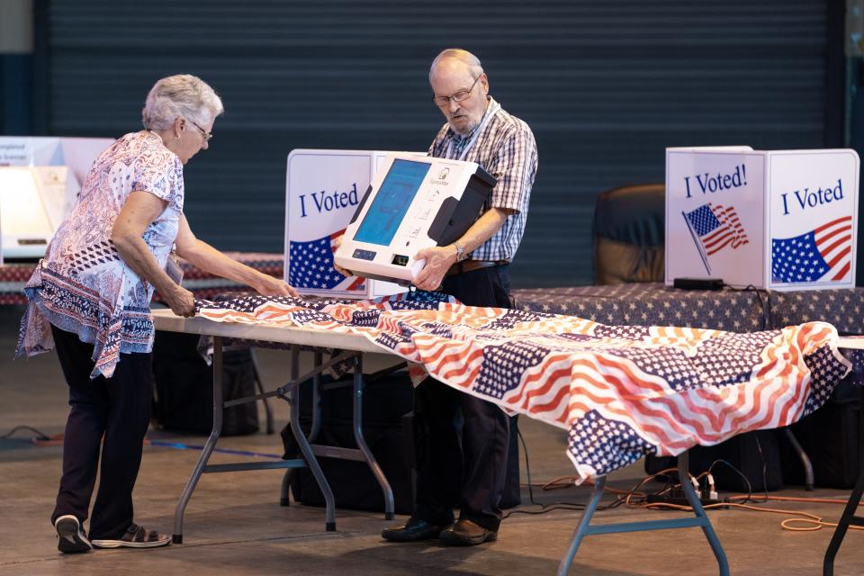 Poll workers Ron Jezowski (R) and Peggy Langdale adjust a table with a voting machine during midterm primary elections on June 14, 2022 in West Columbia, South Carolina.