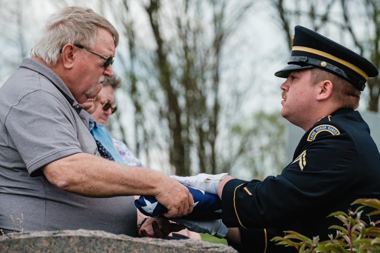 William Wesley Garner receives an American flag from his grandson, Cpl. Korben William Spurlock of the Ohio Army National Guard Honor Guard, during a military honors ceremony Friday for World War II veteran William Clyde Garner at Patterson-Union Cemetery in Deersville. William Clyde Garner died in 1980, but was not given honors.