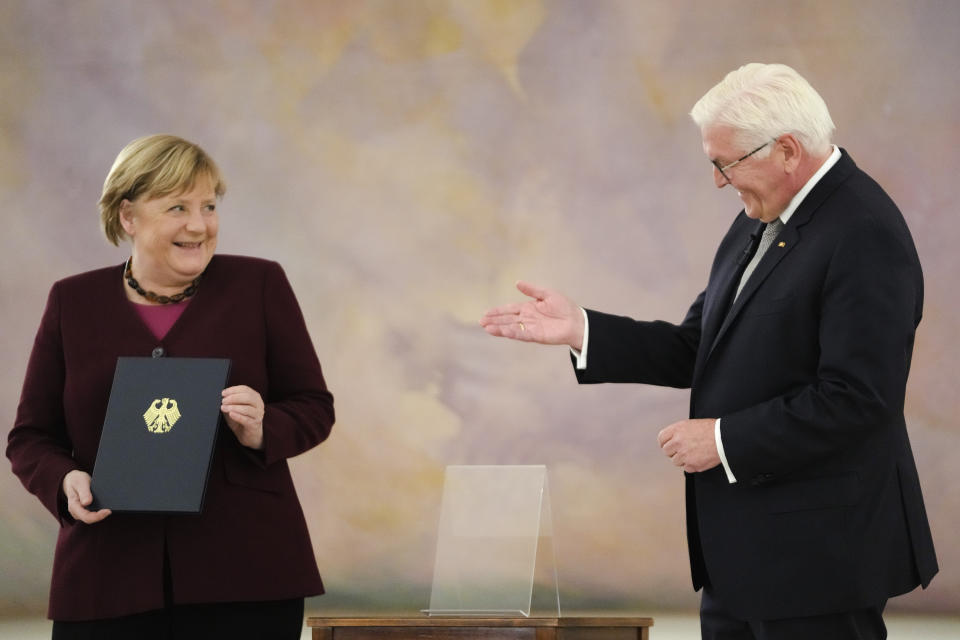 German Chancellor Angela Merkel, left receives her certificate of dismissal from German President Frank-Walter Steinmeier in Berlin, Tuesday, Oct. 26, 2021. Merkel stays in office until a successor is elected. (AP Photo/Markus Schreiber)