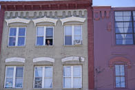 A woman leans out of a window to smoke in Ellenville, N.Y., Wednesday, June 16, 2021. Less than 100 miles north of New York City, Ulster County is popular destination for weekenders headed to Woodstock or the Catskill Mountains. Though pretty, there are pockets of poverty. The county is working with the Center for Guaranteed Income Research at the University of Pennsylvania on a pilot program funded by private donations. One hundred households making less than $46,900 a year in May began receiving a $500 payment each month for a year. Recipients of the money can spend it as they wish, but will be asked to participate in periodic surveys about their physical health, mental health and employment status. (AP Photo/Seth Wenig)