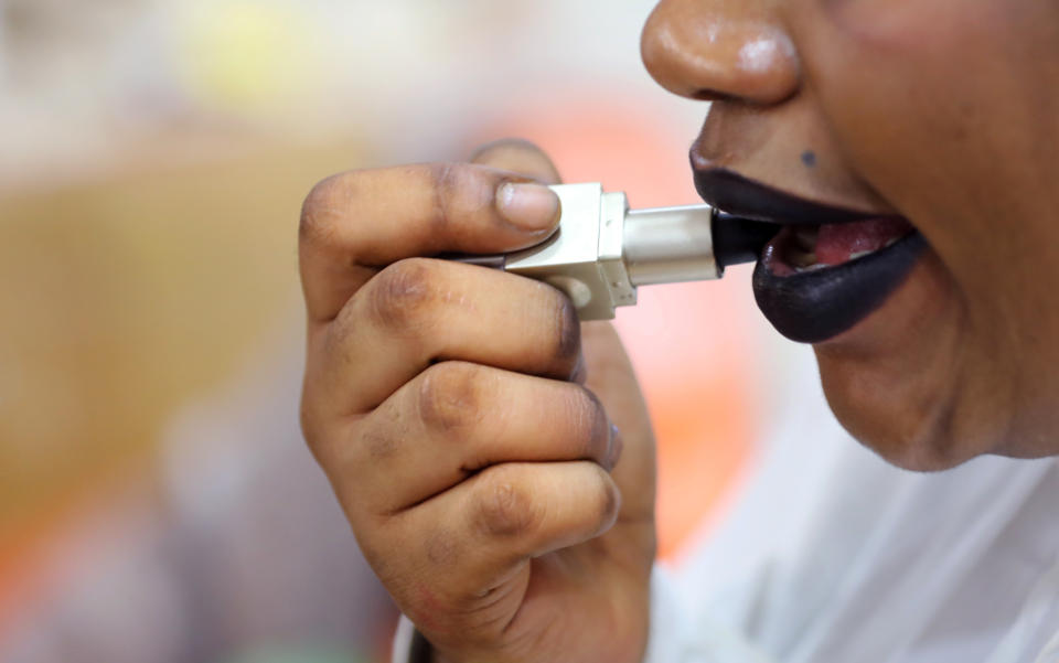 A woman puts lipstick on her lips in a beauty salon in Abidjan, Ivory Coast, May 22, 2019. REUTERS/Thierry Gouegnon