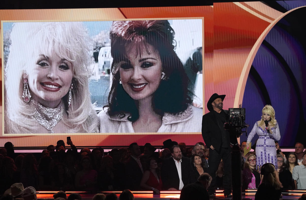 The late singer Naomi Judd appears onscreen during an In Memoriam tribute, while host Garth Brooks and Dolly Parton speak onstage at the 58th annual Academy of Country Music Awards on Thursday, May 11, 2023, at the Ford Center in Frisco, Texas. (Photo: AP/Chris Pizzello)