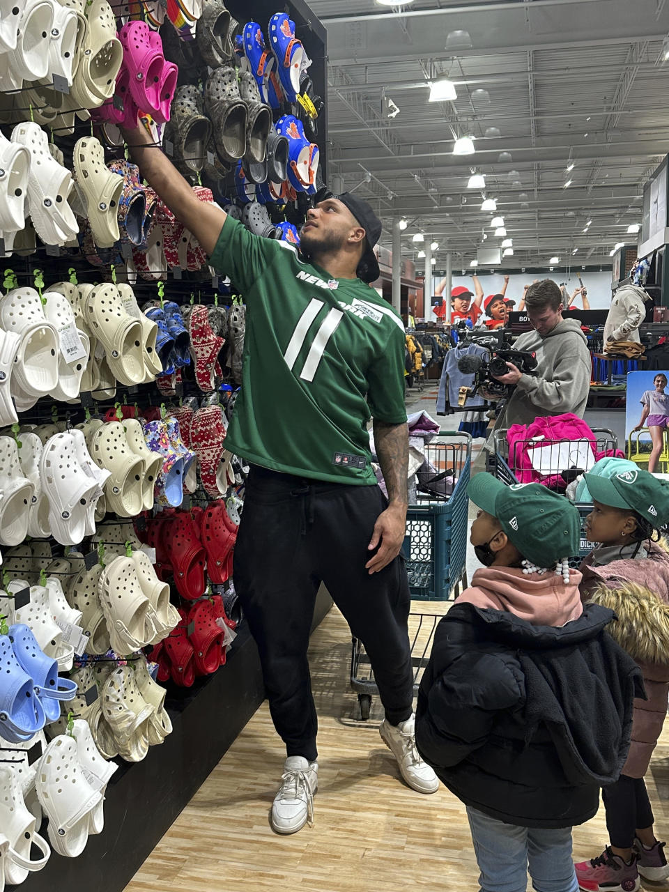 New York Jets linebacker Jermaine Johnson helps young students from Brooklyn Community Services Jets' Academy during a holiday shopping spree hosted by the team at Dick's Sporting Goods in East Hanover, N.J., on Tuesday, Dec. 12, 2023. (AP Photo/Dennis Waszak Jr.)