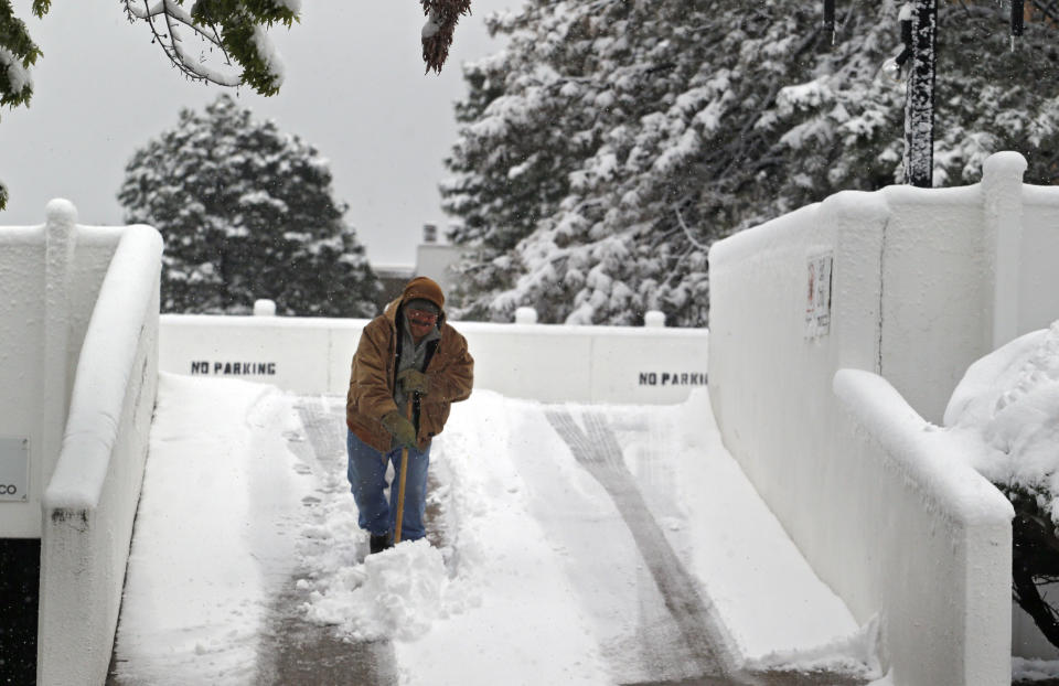 Hector Rodrigues clears snow from a driveway to a parking structure in Denver on Monday, May 12, 2014. A spring storm that has brought over a foot of snow to parts of Colorado, Wyoming and Nebraska and thunderstorms and tornadoes to the Midwest was slowing down travelers and left some without power Monday morning. (AP Photo/Ed Andrieski)