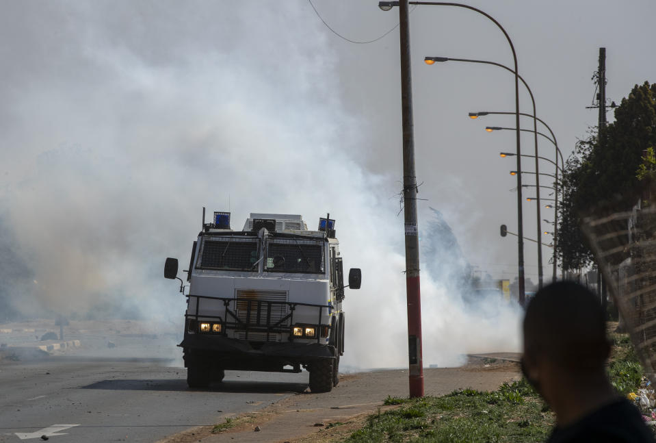 A police vehicle chases protesters in Eldorado Park, Johannesburg, South Africa, Thursday, Aug. 27, 2020. Residents from the township, south of Johannesburg are demanding justice for a teenager shot and killed, allegedly at the hands of police Wednesday. (AP Photo/Themba Hadebe)