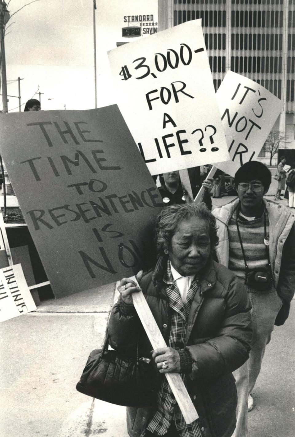 Marchers carry signs calling for harsher penalties for the killers of Vincent Chin.