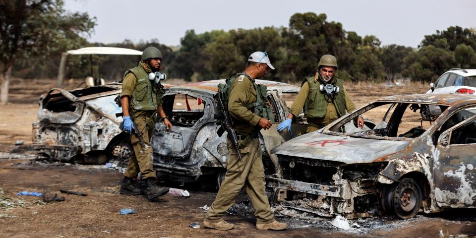 Israeli soldiers inspect burnt cars