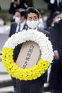 Japanese Prime Minister Shinzo Abe carries the wreath to offer during a ceremony to mark the 75th anniversary of the U.S. atomic bombing at the Peace Park in Nagasaki, southern Japan Sunday, Aug. 9, 2020. (Kyodo News via AP)