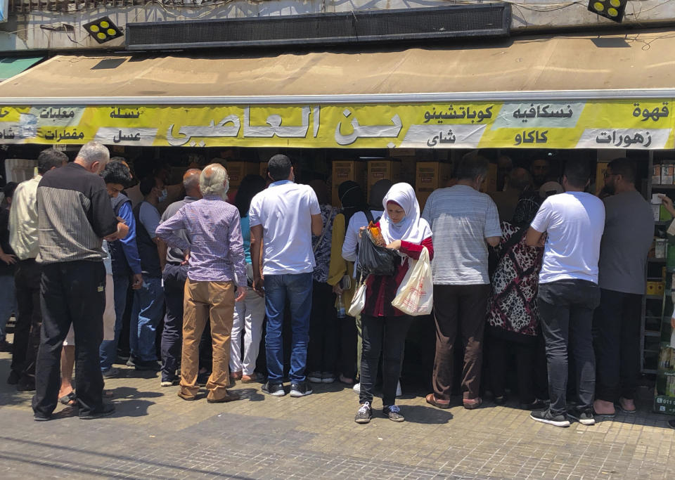 People stand in line outside a roastery in Beirut to buy coffee fearing there will be shortages after the price of beans increased, in Beirut, Lebanon, Wednesday, June 23, 2021. Lebanon is struggling amid a 20-month-old economic and financial crisis that has led to shortages of fuel and basic goods like baby formula, medicine and spare parts. The crisis is rooted in decades of corruption and mismanagement by a post-civil war political class. (AP Photo/Hussein Malla)