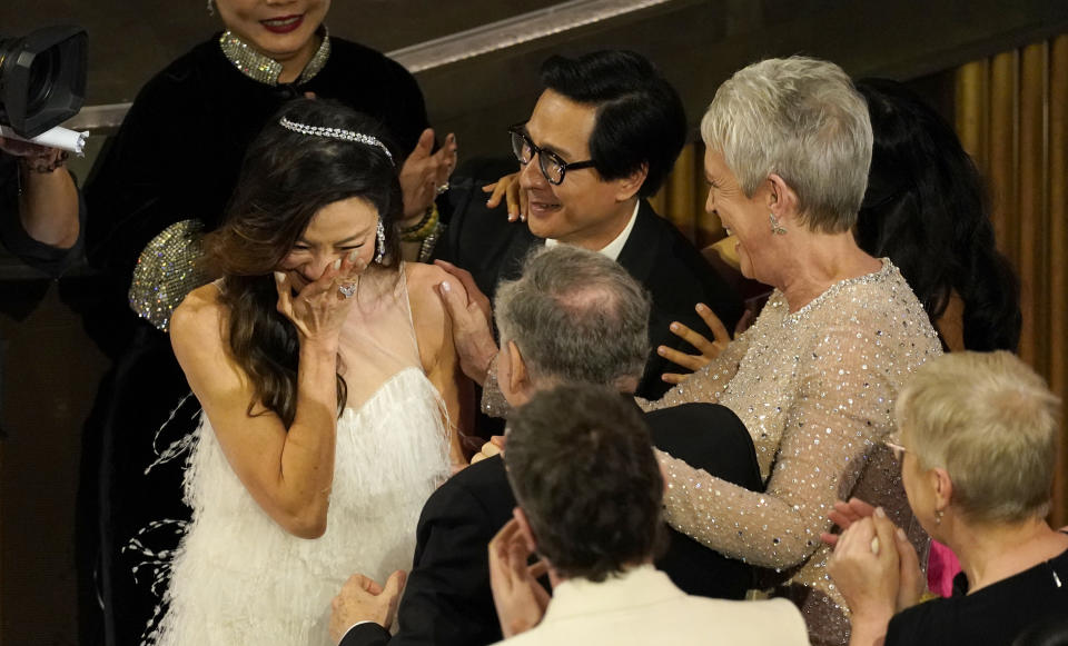 Michelle Yeoh, izquierda, reacciona emocionada entre el público al recibir el premio a mejor actriz por "Everything Everywhere All at Once" en los Oscar el domingo 12 de marzo de 2023 en el Teatro Dolby en Los Angeles. Jamie Lee Curtis, de derecha a izquierda, y Ke Huy Quan están junto a Yeoh. (Foto AP/Chris Pizzello)