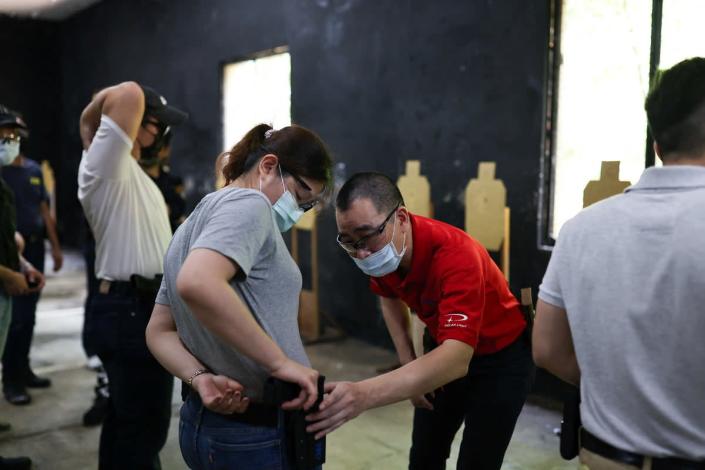 A trainer checks if a female trainee’s airsoft handgun is placed correctly in the holster during a basic training class (Reuters)