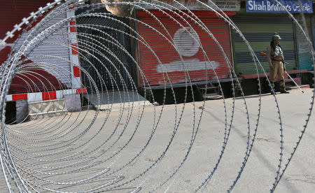 An Indian policeman stands guard next to concertina wire laid across a road during a curfew in downtown Srinagar, India, September 20, 2016. REUTERS/Danish Ismail