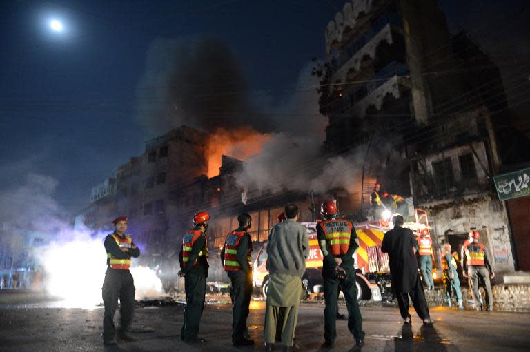 Security personnel gather outside a burning market after sectarian clashes near a Sunni mosque during the Shiite Muslim procession in Rawalpindi on November 15, 2013