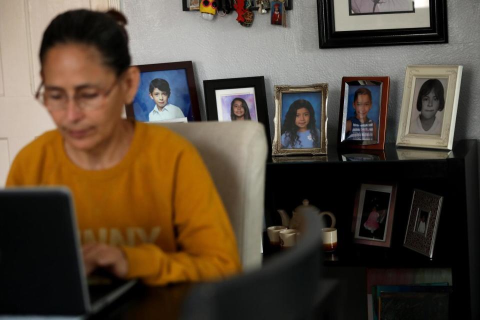 Claudia Aleman works on her computer with photos of her family in the background