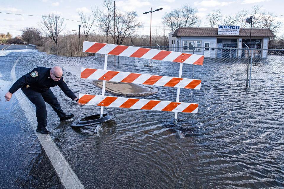 Captain Dempsey of the New Castle Police Department hauls back street barricades displaced by strong winds near a flooded zone on East 6th Street along Chestnut Street and Wilmington Road in New Castle, Wednesday, Jan. 10, 2024. The floods resulted from an overnight storm of strong winds and rain.