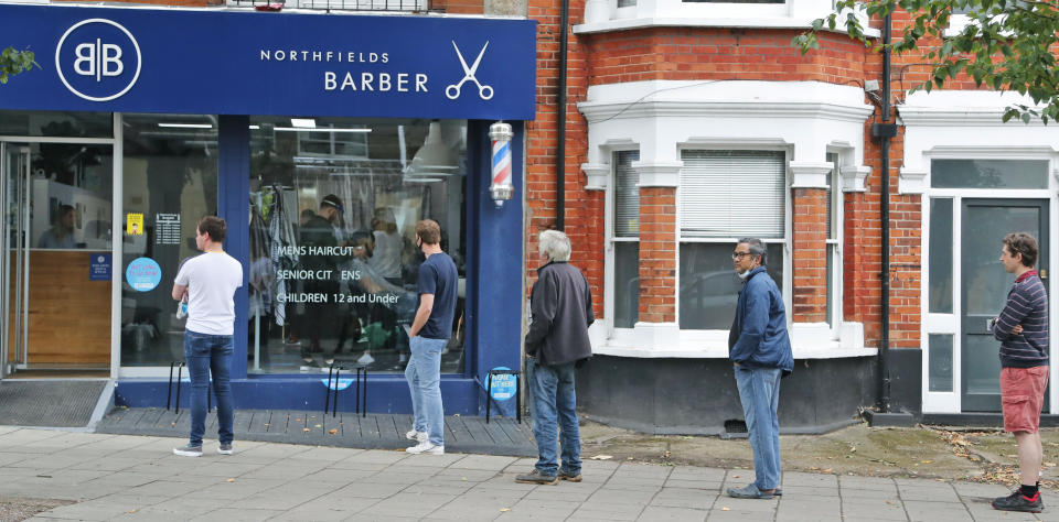 People queue outside Northfields Barber as it opens for the first time after the COVID-19 lockdown in London, Saturday, July 4, 2020. England is embarking on perhaps its biggest lockdown easing yet as pubs and restaurants have the right to reopen for the first time in more than three months. In addition to the reopening of much of the hospitality sector, couples can tie the knot once again, while many of those who have had enough of their lockdown hair can finally get a trim. (AP Photo/Frank Augstein)