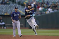 Seattle Mariners shortstop J.P. Crawford, middle, throws out Oakland Athletics' David MacKinnon at first base during the second inning of a baseball game in Oakland, Calif., Friday, Aug. 19, 2022. (AP Photo/Jeff Chiu)