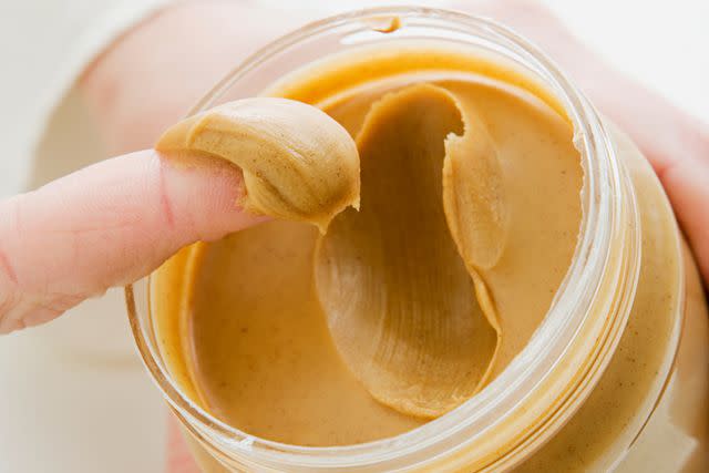 <p>Getty</p> Stock image of peanut butter on someone's finger.