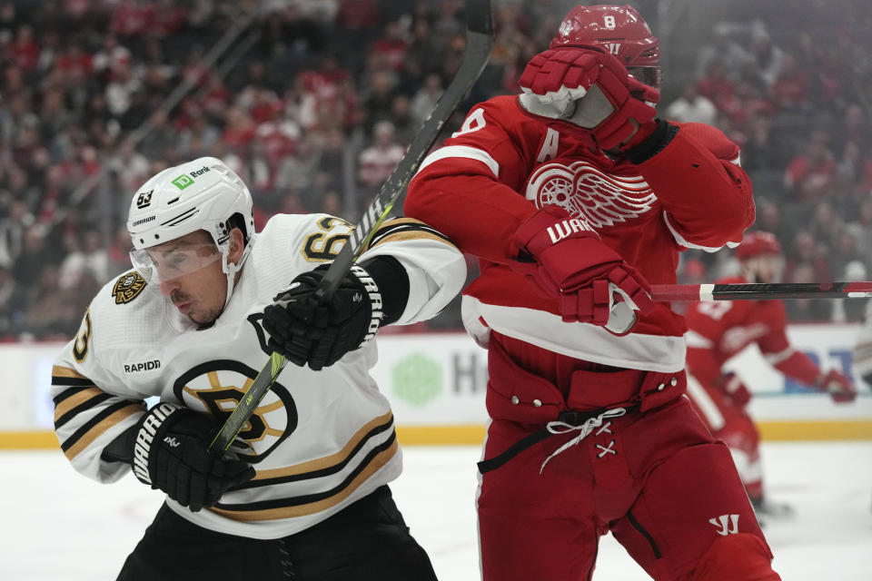 Boston Bruins left wing Brad Marchand (63) is checked by Detroit Red Wings defenseman Ben Chiarot (8) during the first period of an NHL hockey game Saturday, Nov. 4, 2023, in Detroit. (AP Photo/Carlos Osorio)