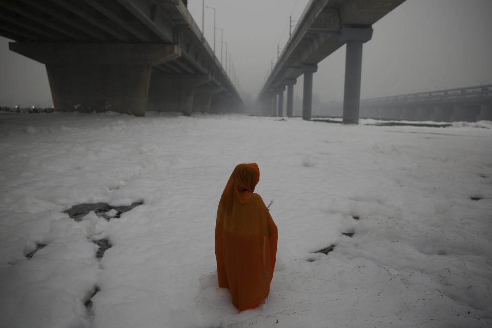 In this Saturday, Nov. 2, 2019, file photo, an Indian Hindu devotee performs rituals in Yamuna river, covered by chemical foam caused due to industrial and domestic pollution, during Chhath Puja festival in New Delhi, India. During Chhath, an ancient Hindu festival, rituals are performed to thank the sun god for sustaining life on earth. (AP Photo/Altaf Qadri, File)