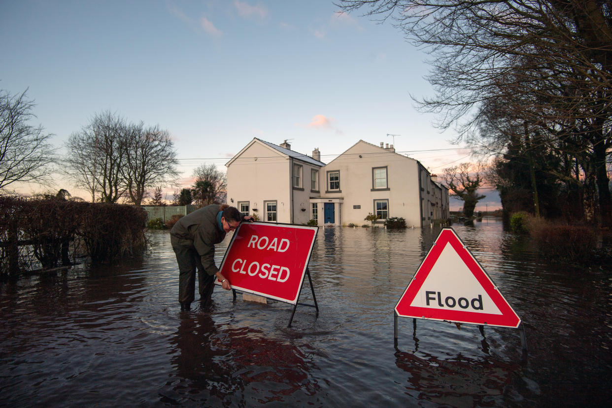 Gabrielle Burns-Smith erects a road closed sign on Warrington Lane on the outskirts of Lymm in Cheshire as Storm Christoph causes widespread flooding across the UK. Picture date: Thursday January 21, 2021.