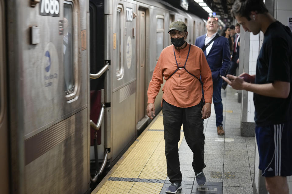 Commuters, one wearing a mask, wait to board the subway in New York, Friday, June 14, 2024. New York Gov. Kathy Hochul says she is considering a ban on face masks in the New York City subway system, following what she described as concerns over people shielding their identities while committing antisemitic acts. (AP Photo/Seth Wenig)