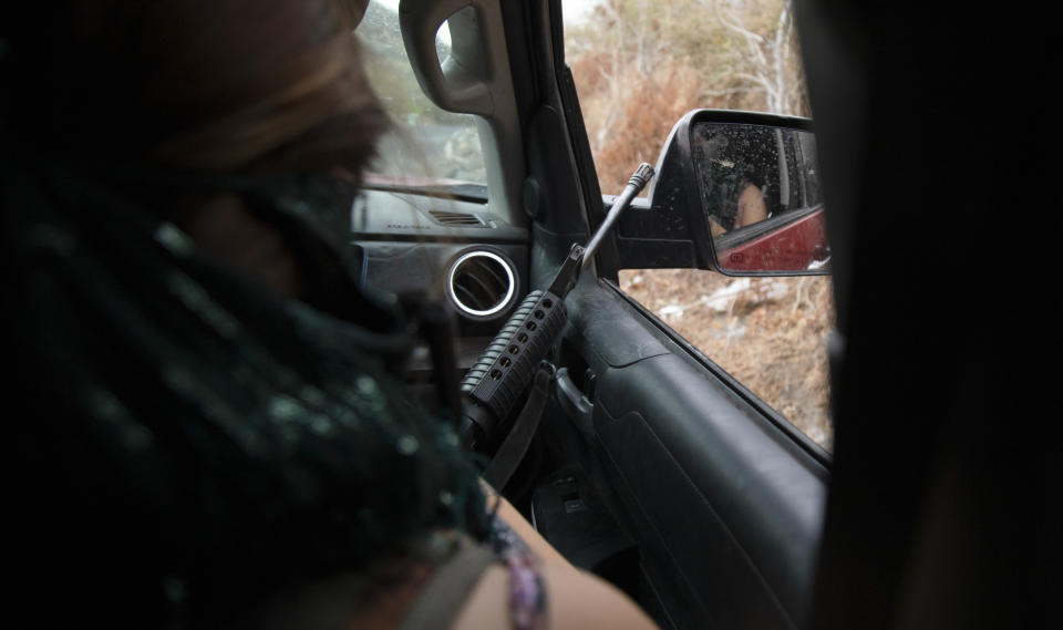 An armed woman known as "La Guera," who says she is a member of a female-led, self-defense group, patrols the edge of their town of El Terrero, where it shares a border with the town of Aguililla, in Michoacan state, Mexico, Thursday, Jan. 14, 2021. The vigilantes bitterly deny allegations they're part of a criminal gang, though they clearly see the Jalisco cartel as their foe. They say they would be more than happy for police and soldiers to come in and do their jobs. (AP Photo/Armando Solis)