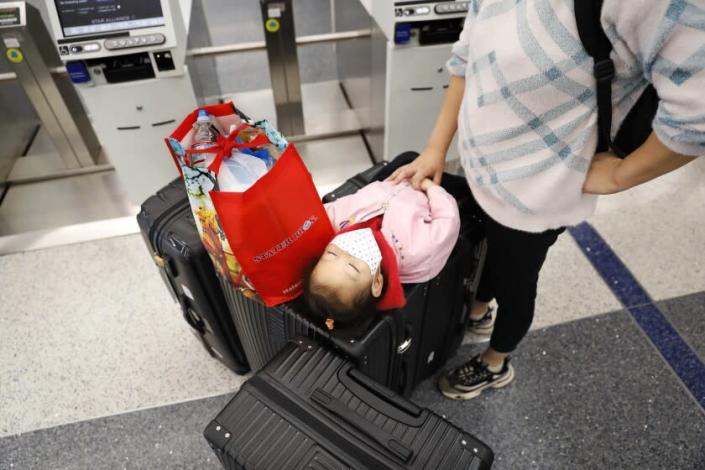 LOS ANGELES-CA-DECEMBER 27, 2021: A young traveler takes a rest on top of the family&#39;s luggage at LAX on Monday, December 27, 2021. At least 87 flights in or out of LAX were canceled Sunday, affecting some holiday travelers. (Christina House / Los Angeles Times)