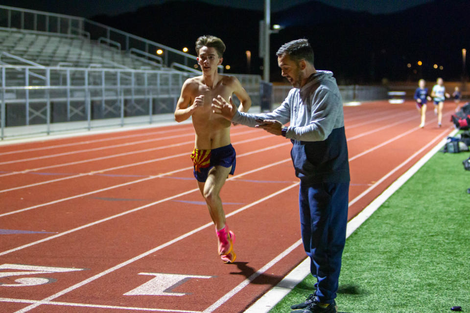 Brayden LeVander finishes a lap during practice at ALA West Foothills High School in Waddell, Ariz., on Feb. 13, 2024. His father and coach Jason LeVander yells out his time.