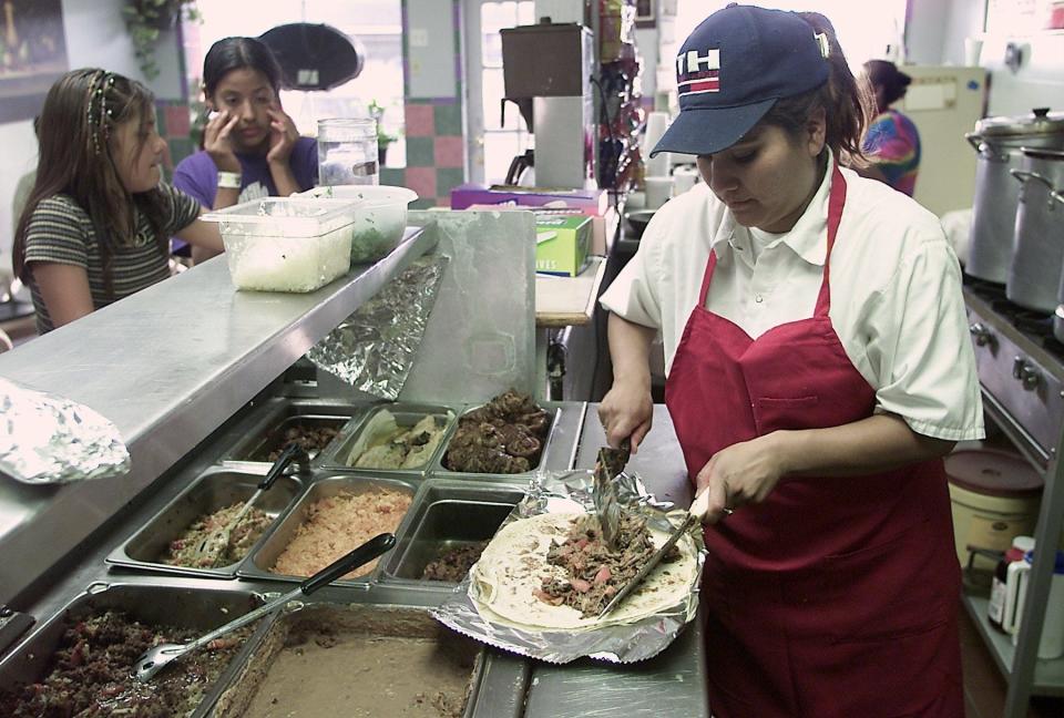 2002: Alice the Burrito Lady employee Rosa Ruiz served burritos to Claudia Gaytan, 11, left, and Jazmine Martinez, 11, Wednesday evening.