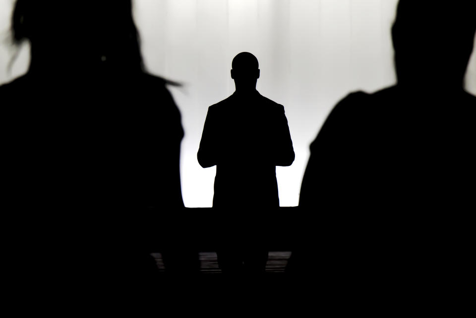 Silhouettes of a mystery man standing , watching and confronting two blurry persons in the dark