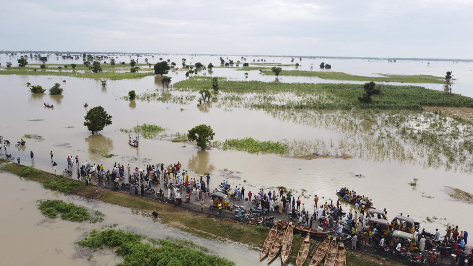 FILE - People walk through floodwaters near flooded farmlands after heavy rainfall in Hadeja, Nigeria, Sept 19, 2022 .Authorities in Nigeria say they have activated a national response plan for another round of deadly floods blamed mainly on climate change and infrastructure problems. The West African nation's National Emergency Management Agency said Thursday, July 6, 2023 it has begun to work based on dire forecasts by seeking air support for search and rescue missions while stockpiling relief materials. (AP Photo, file)