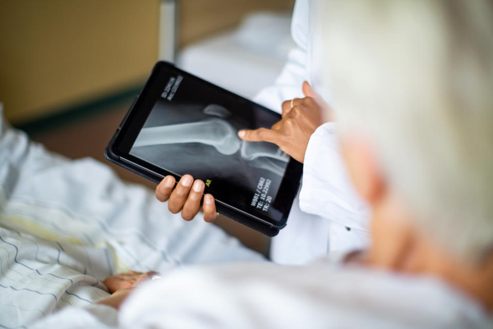 Cropped shot of a female doctor showing result of radiography on digital tablet to patient and giving diagnosis. Doctor talking to patient about medical treatment after surgery.