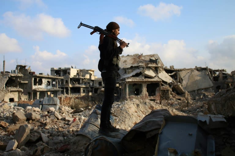 A rebel fighter stands amid destroyed buildings in Daraa in southern Syria on March 14, 2017